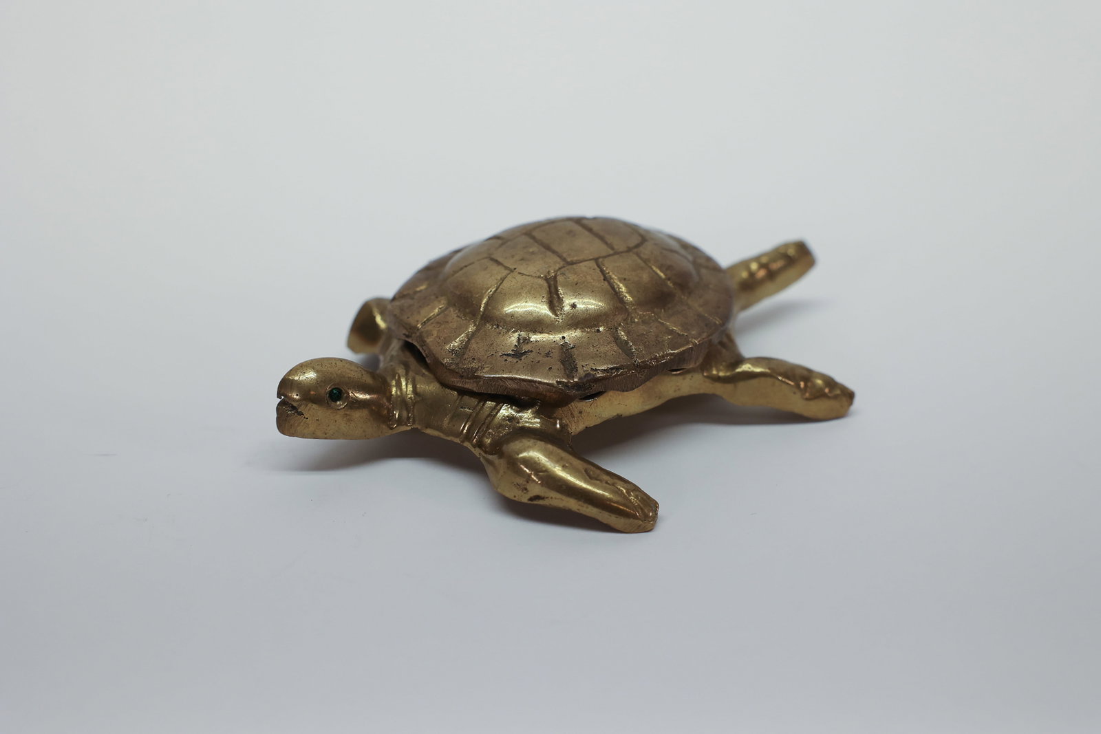 Brass Turtle-Form Ashtray with Lift-Off Shell Lid: Cast brass figural turtle ashtray/trinket dish. Textured shell lid lifts completely off to reveal a shallow oval well beneath. Sculpted head, tail, and four legs with articulated toes; inset green
