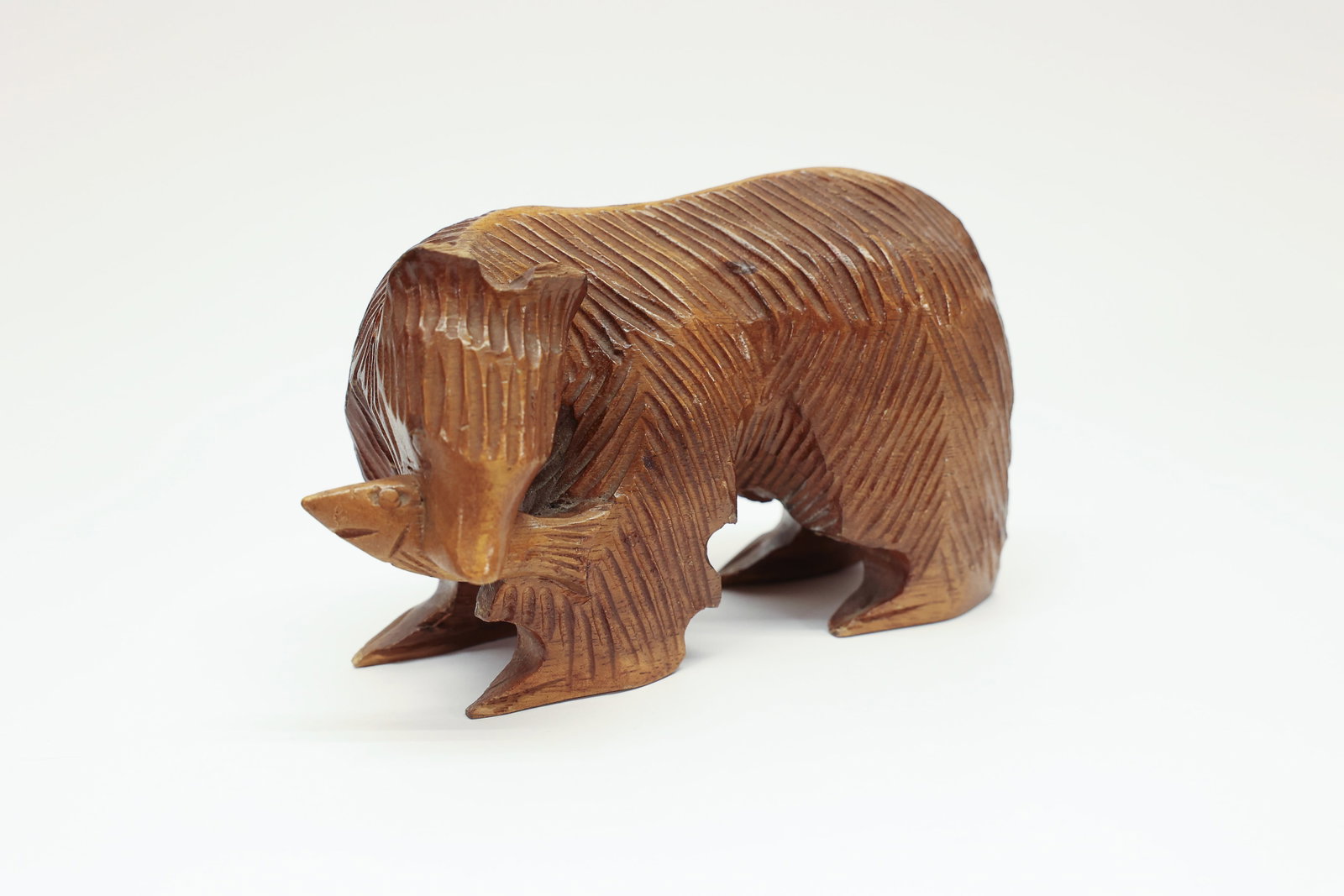 Carved Wood Bear with Fish Figurine, Black Forest: Hand-carved wood figure of a walking bear with deeply incised fur texture throughout, head lowered with a carved fish held in its mouth. Black Forest-style folk carving.Dimensions: H: 3.75", W: 3",
