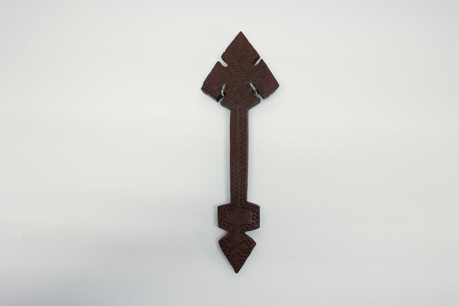 Carved Wood Folk Art Tramp Art w/ Hanger: Hand-carved wood in an arrow/cross form with dense chip-carved geometric patterning throughout, wire hanger on the reverse. Folk/tramp art style.Dimensions: H: 0.5", W: 3.25", L: 10"