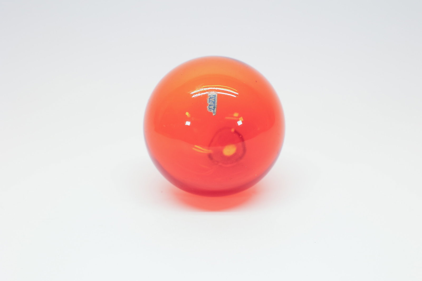 Japanese Blown Glass Fishing Float, Amberina, 3": Genuine hand-blown Japanese glass fishing float in a rich amberina/orange tone, measuring approximately 3" in diameter. The float retains its original small paper "Japan" label, along with the seal