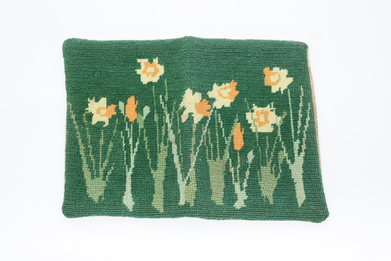 Antique Berlin Wool Work Needlepoint Book Cover: Antique hand-stitched wool needlepoint book cover in a padded pillow-style design, featuring cross-stitched daffodils in gold and orange against a deep green ground, with a silk or silk-like grosgrain