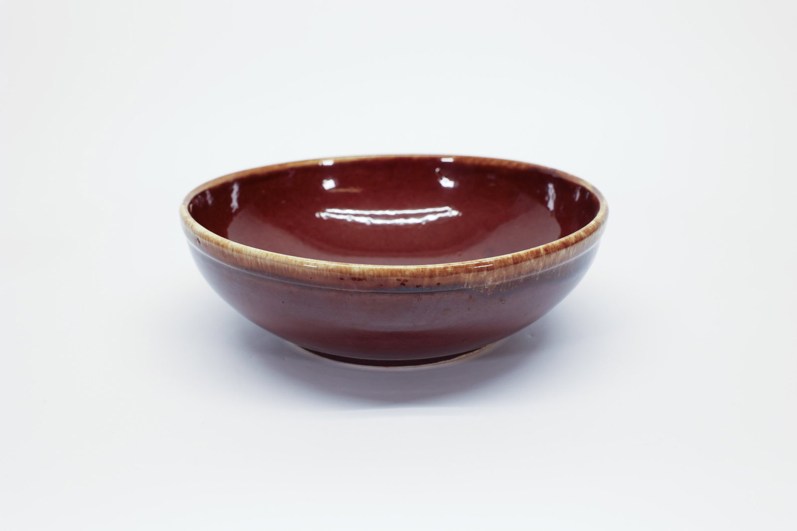 Kathy Kale Mid-Century Pottery Bowl: Mid-20th century American production pottery bowl, featuring a rich brown glaze pooling into deeper tones at the center and a warm honey-toned drip along the rim. The wide, shallow form is typical of 