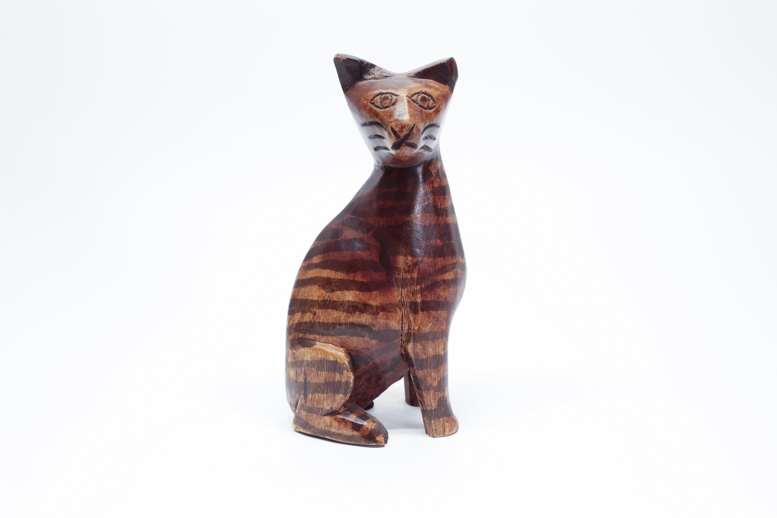 Carved Wood Tiger-Stripe Cat Figure, Folk Art: Hand-carved wooden cat figure in a seated pose, featuring a naturally striped, tiger-like grain pattern in warm honey and dark walnut tones, with simple incised facial features including almond-shaped