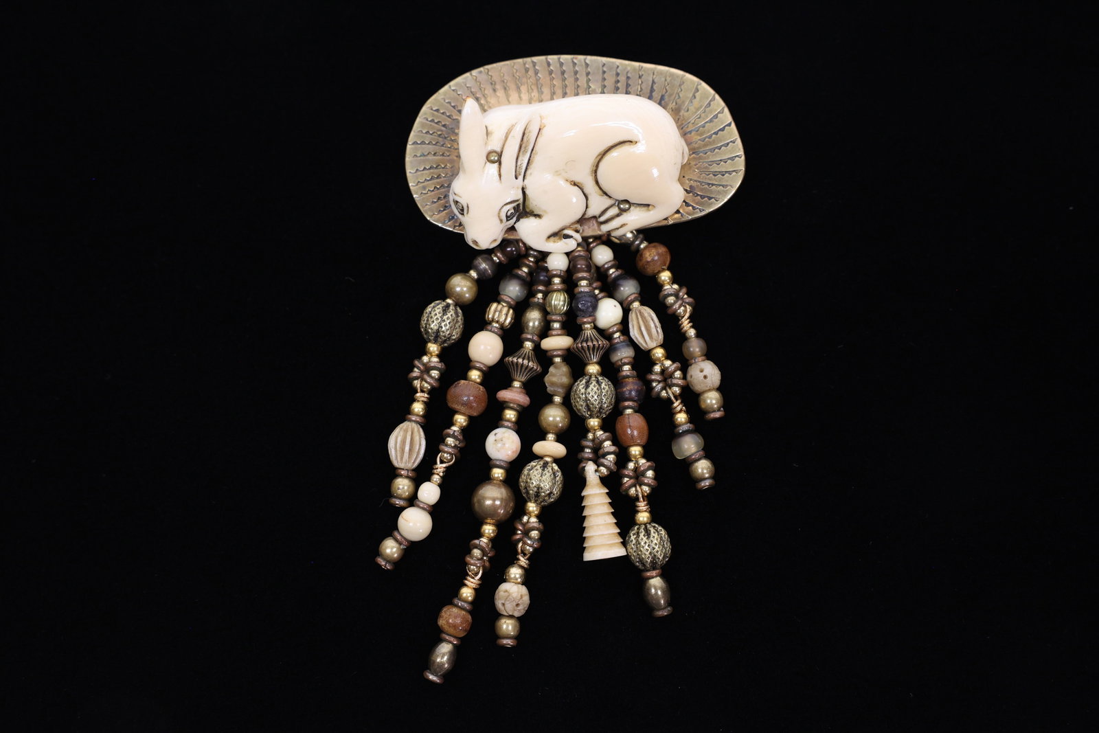 Signed Navarro Carved Bone Rabbit Fringe Brooch: A charming piece of studio art jewelry, this brooch pairs a hand-carved bone (or bone-style resin) rabbit figure — its fur, eye, and haunch lines incised by hand — with a hammered, sunburst-engrav