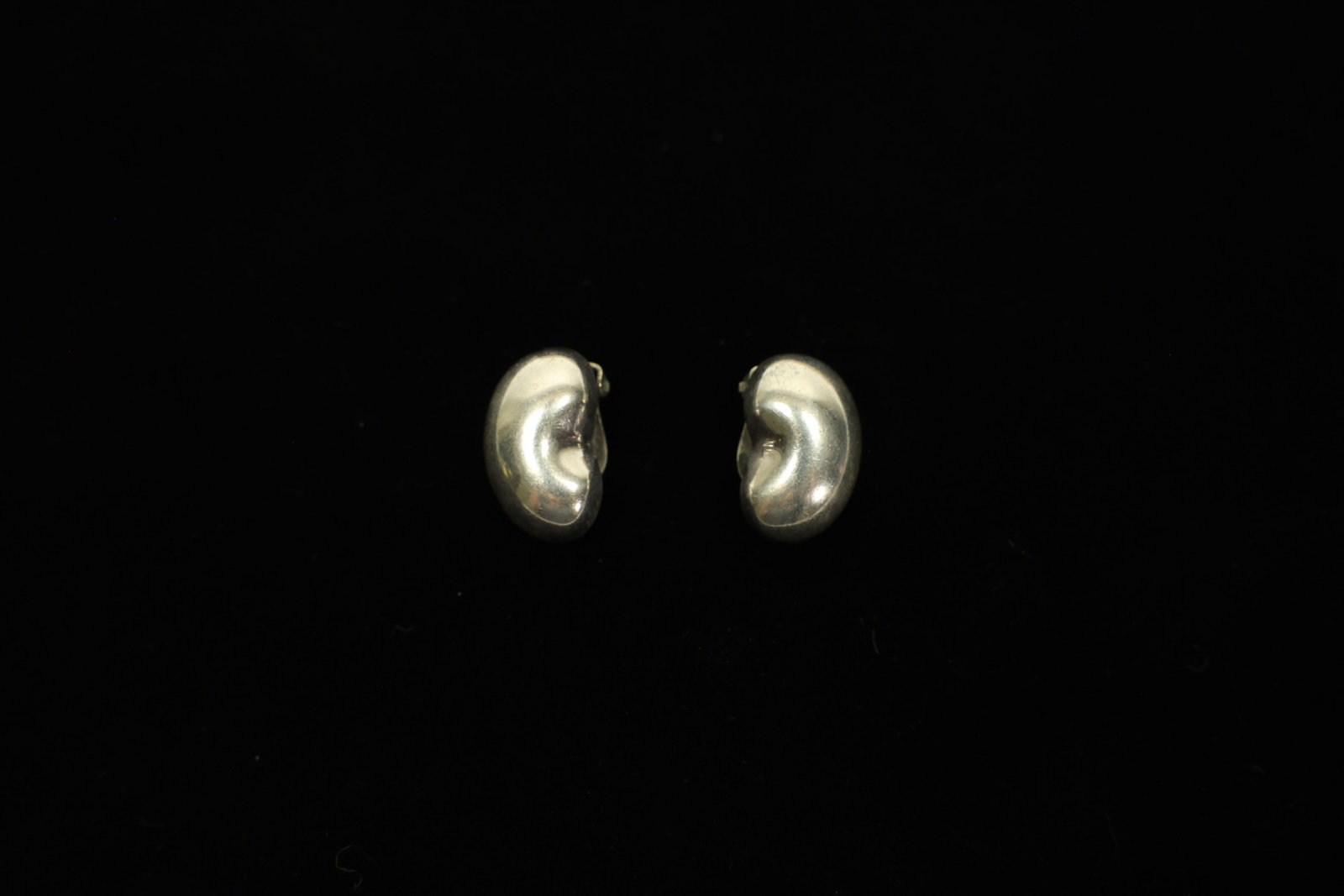 Vahan Sterling Silver Bean Clip Earrings: A polished pair of sterling silver "bean" earrings, each modeled as a plump, curving bean shape with a deeply mirrored high-polish finish that catches the light from every angle. Stamped "VAHAN" on th