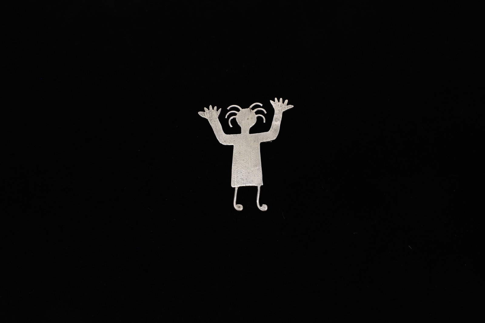 Sterling Silver Southwestern Petroglyph Man Pin: A whimsical sterling silver brooch cut and formed into the shape of a stylized human figure with wild, spiky hair, raised arms with splayed fingers, and curling, dancer-like feet. The design draws dir