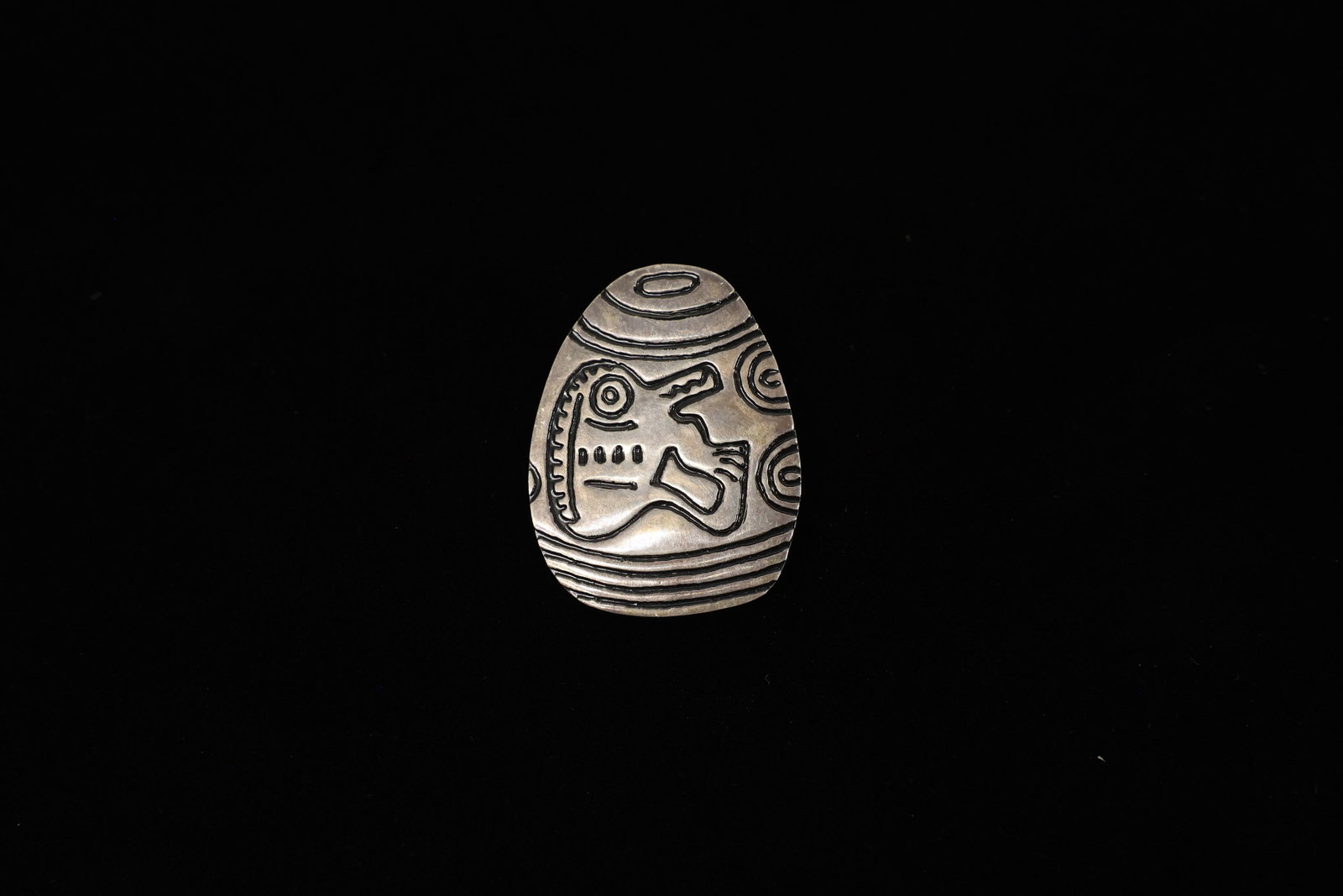 Sterling Silver Etched Petroglyph Style Brooch: This sterling silver (925) brooch is shaped like a smooth river pebble or egg and hand-etched with a bold, primitivist design: a stylized zoomorphic creature with a toothy, open jaw, a circular eye, a