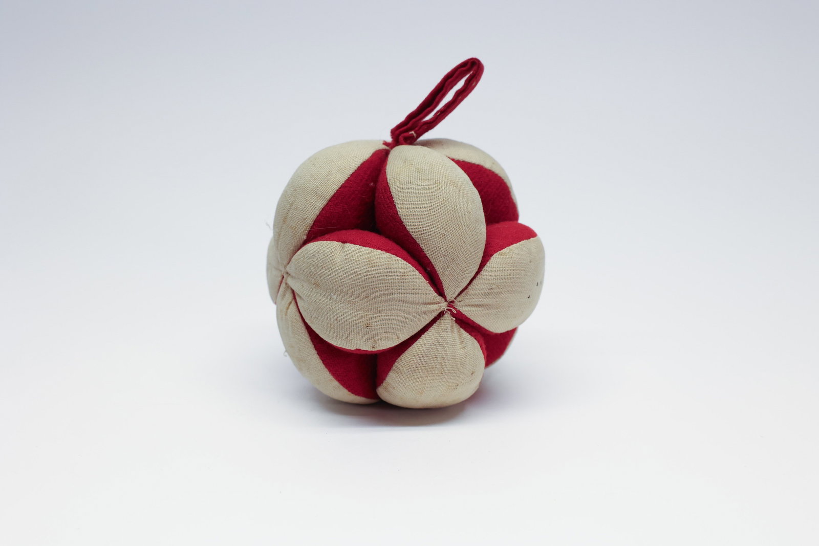 Antique Amish Folk Art Puzzle Ball, Cream & Red: This charming hand-sewn sphere, measuring 4 1/2" in diameter, is an example of the traditional Amish puzzle ball, a folk-craft technique in which individually cut and folded fabric petals are