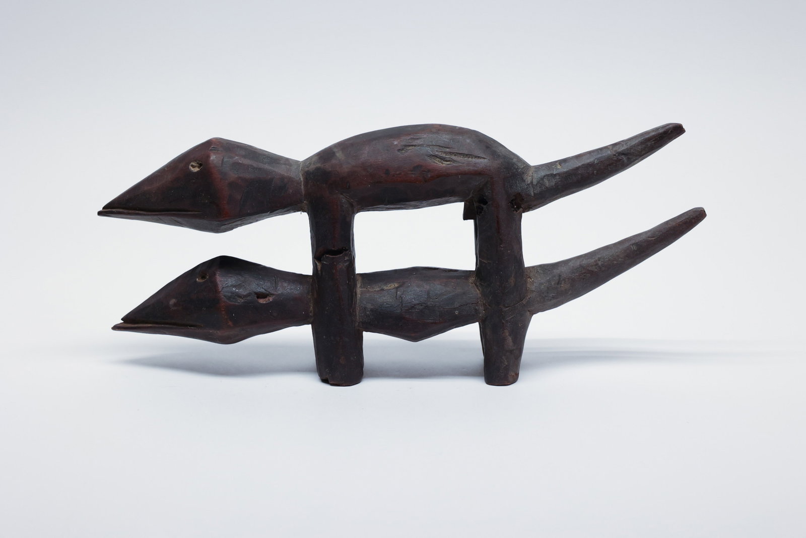 Tribal Carved Wood Mating Lizards Effigy: This 11.5" hand-carved wooden effigy depicts a pair of lizards joined in mating position, their long, tapering bodies and pointed snouts stretching outward in opposite directions from a shared, rounde