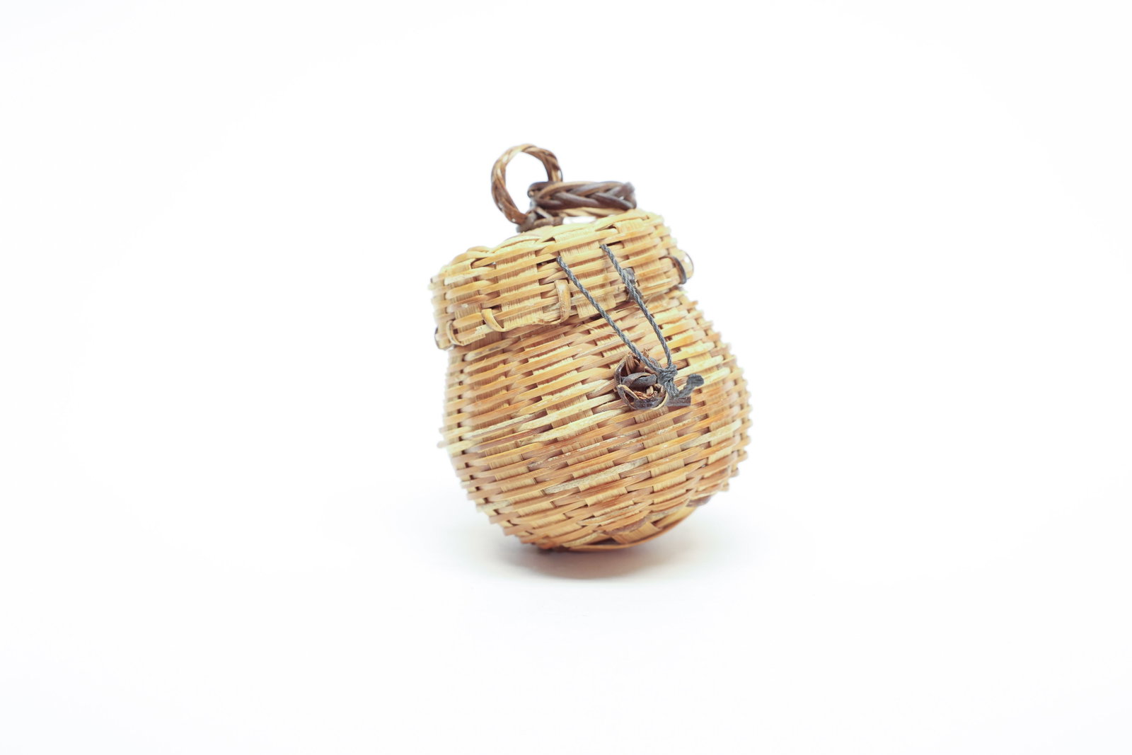 Miniature Woven Splint Basket with Lid: A charming miniature woven basket, 3.5" tall, in a rounded, barrel-like form with a fitted lid and a twisted, rope-like carrying loop at top. The body is tightly woven from thin splint or reed strips 