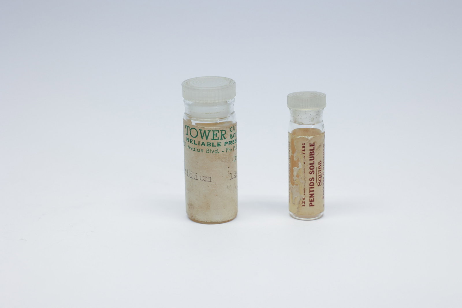 Vintage Pharmacy Vials, Tower & Squibb Pentids: A pair of vintage pharmacy vials with period-correct labels. The larger vial is labeled "Tower Reliable Prescriptions, 9501 Avalon Blvd." with "Pyridium" typed in, while the smaller vial carries a pri