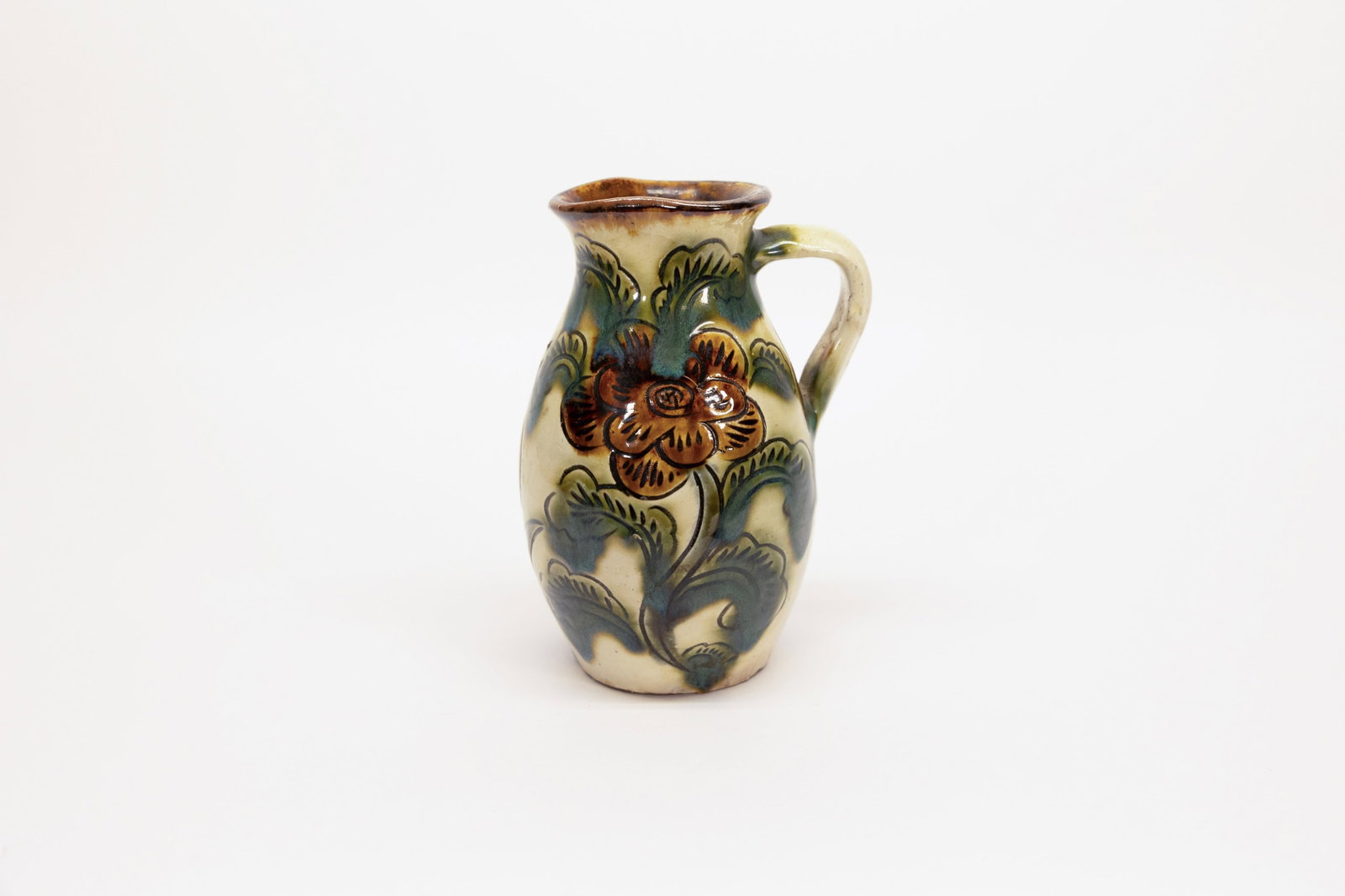 Japanese Mid Century Fish Woman Pottery Pitcher: Description:Small hand-thrown studio pottery pitcher, Japanese, mid-20th century, with a cream/ivory glaze ground decorated on one side with a large stylized flower and leaf motif in amber, brown, and