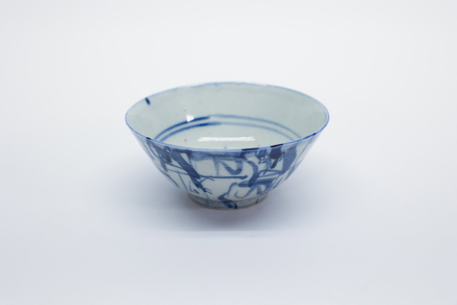 Chinese Blue White Porcelain Bowl, Grass Script: Description:Chinese porcelain bowl with a flared rim tapering to a narrow footring, decorated in underglaze cobalt blue with a loose, calligraphic "grass script" style motif wrapping the exterior, pai