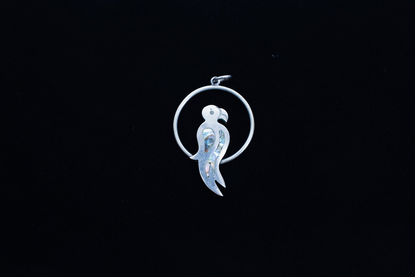 Silver Parrot Pendant, Abalone Inlay: Description:Length 1 3/4"Silver-tone pendant designed as a stylized parrot perched within an open circular hoop, with an inlaid panel of abalone shell forming the bird's body and tail, showing the