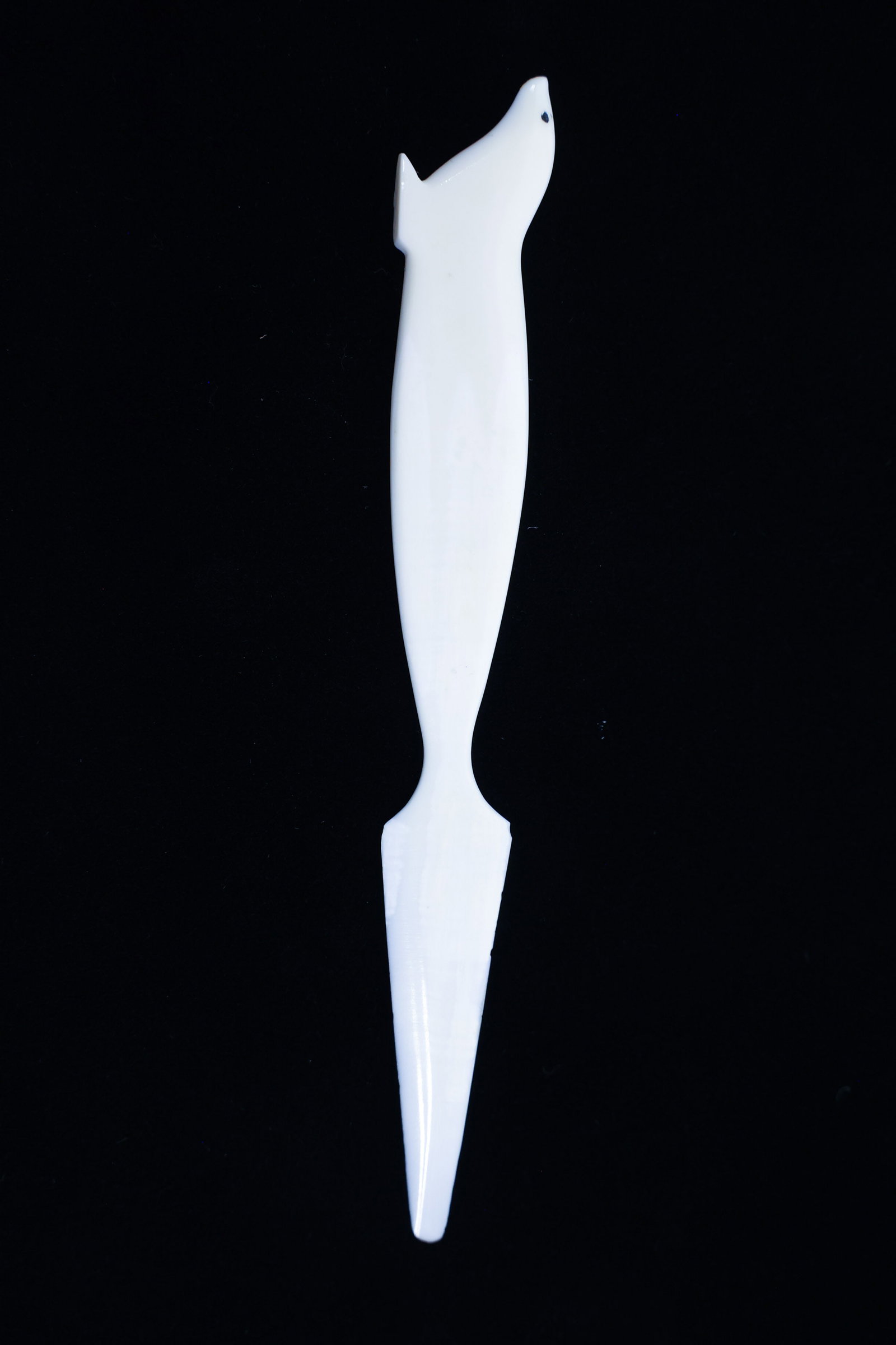Carved Bone Letter Opener, Seal Head Handle: Description:Carved letter opener in a smooth, opaque white bone material, with the handle formed as a stylized seal head, featuring a small painted dot for the eye and simple carved details