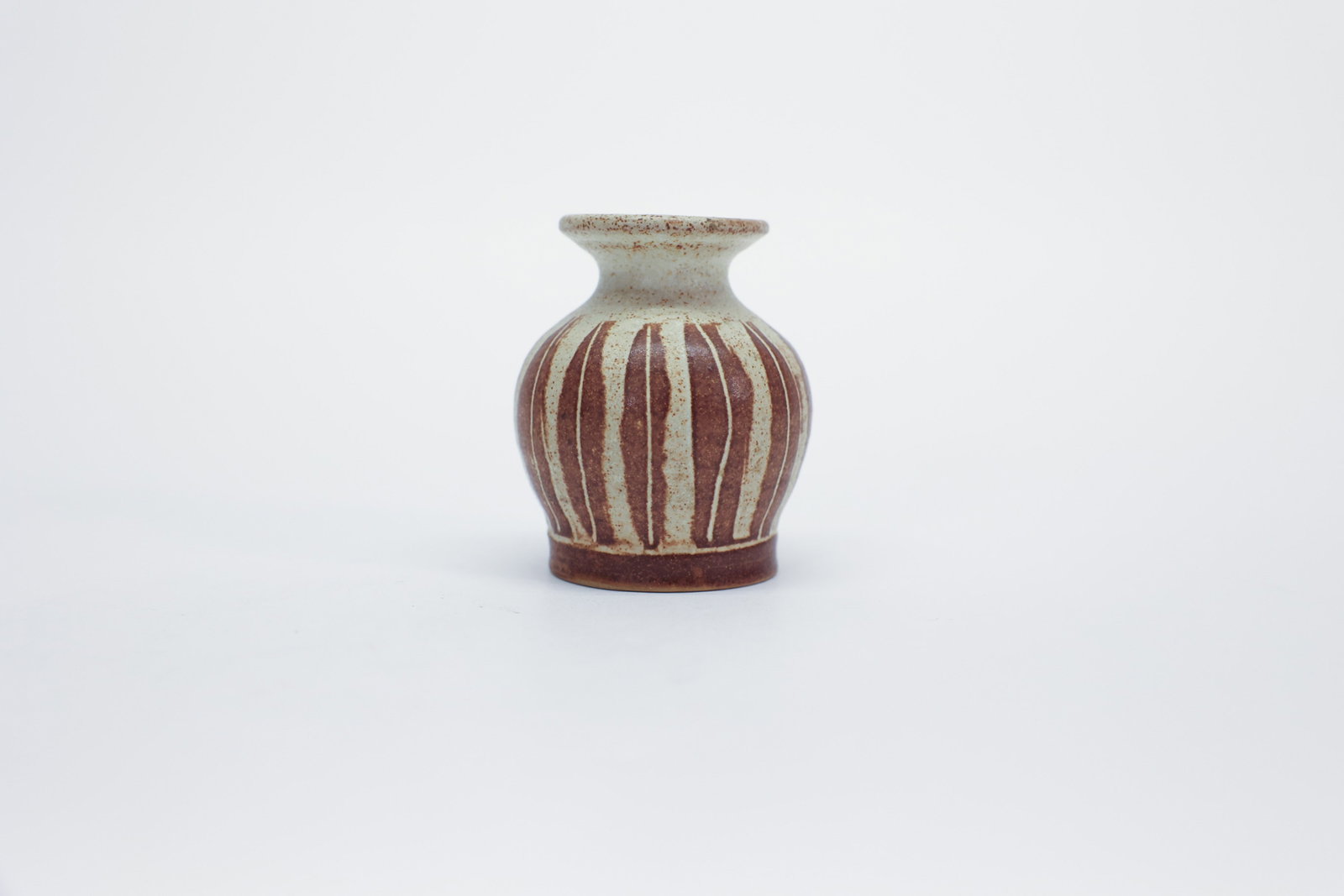 Signed Studio Pottery Bud Vase, Resist Stripe: Description:Small hand-thrown stoneware bud vase with a rounded body and flared trumpet neck, decorated in a speckled rust-red and cream glaze with a vertical resist-stripe pattern encircling the