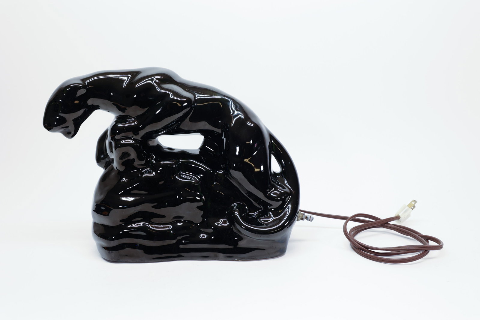 Vintage Black Ceramic Panther TV Lamp, 1950s: Description:Classic mid-century glossy black ceramic panther sculpture, shown in a crouched, stretching pose with head lowered, formed as a "TV lamp" — a decorative sculptural lamp designed to sit