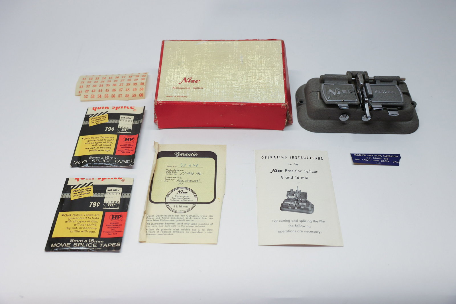 Niezoldi & Krämer Nizo Film Splicer: By Niezoldi & Krämer, a German movie camera and editing equipment company. Tape Splicer. With original box (damaged), instructions, warranty dated 1961, and tapes. Wonderful piece with a bit of it's