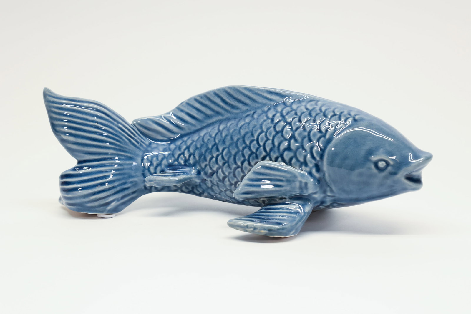 Porcelain Koi Fish Figurine Statue, China/Japan: Elegant ceramic koi fish figurine finished in a soft, monochromatic powder-blue glaze with a glossy finish. Beautifully detailed with overlapping scales, ribbed dorsal and tail fins, and lifelike