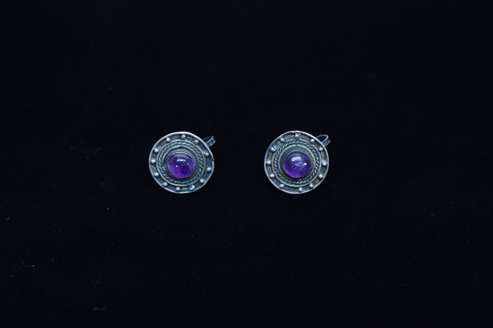 Mexican Sterling Silver Amethyst Clip Earrings VTG: Description:A pair of Mexican sterling silver clip earrings, each set with a round cabochon-cut amethyst at the center of a circular medallion design. The silverwork combines a twisted rope border wit