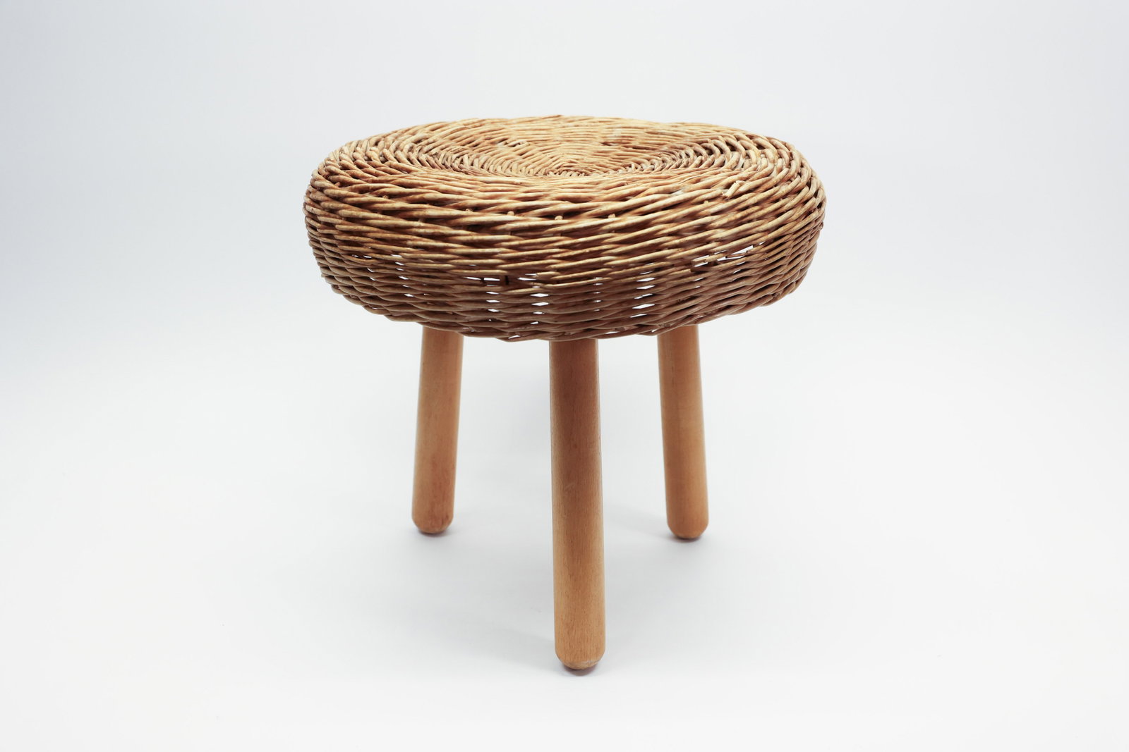 Tony Paul Attributed Wicker Tripod Stool, MCM: Description:A mid-century modern stool in the style of designer Tony Paul, with a thickly coiled woven wicker seat set atop three splayed, turned wooden dowel legs. The seat is built up in a dense,