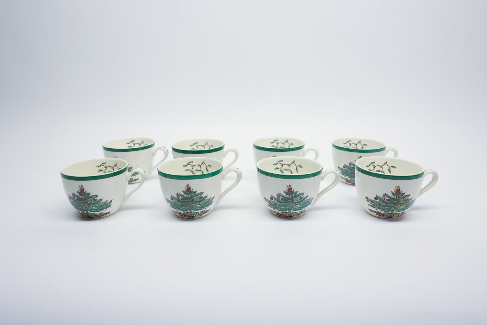 Spode Christmas Tree Cups & Saucers, 8 Sets: Set of eight teacups with matching saucers in Spode's "Christmas Tree" pattern, England. Each cup and saucer decorated with the classic decorated tree, Santa figure, and mistletoe sprig motifs within 