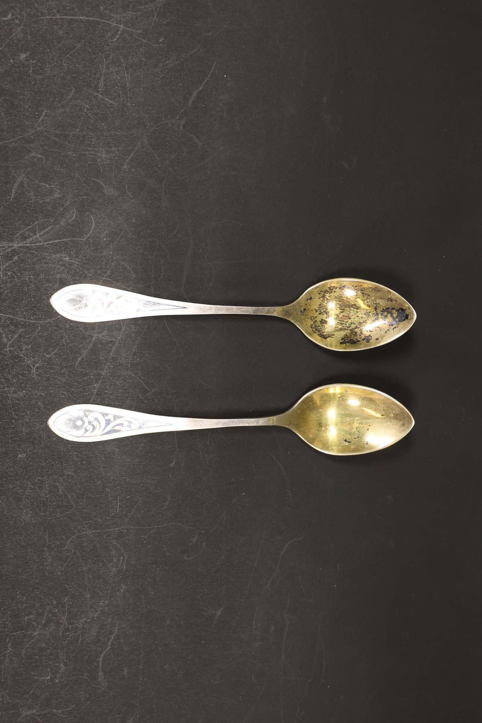 Soviet Russian 875 Silver Niello Spoons, Pair: Pair of Russian silver spoons with gilt-washed bowls and niello (black inlay) floral decoration on the handles. Marked "875" with the Soviet star, hammer, and sickle assay mark, indicating