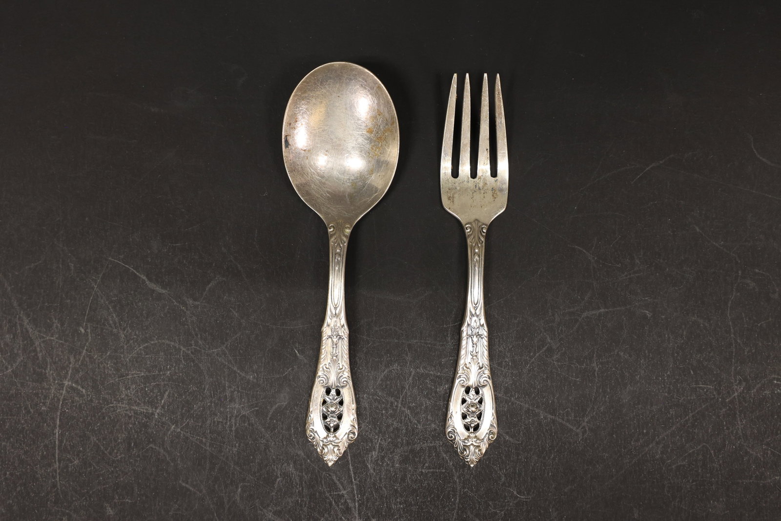 Wallace Sterling Baby Fork and Spoon Set: Child's sterling silver fork and spoon set with a scrolled foliate handle and pierced rose cartouche. Marked "Wallace Sterling" with a stag's-head mark. Total weight 1.271 troy ounces.Dimensions: H: