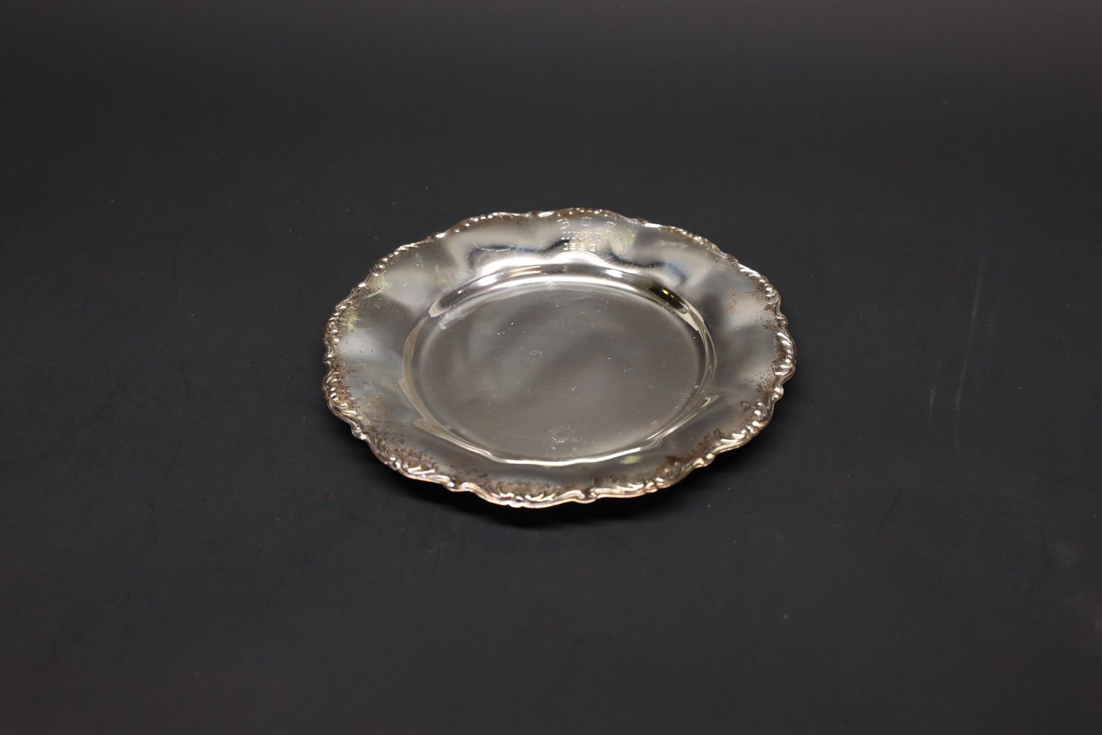 Scalloped Silver-Plate Trophy Dish, 1957: Small round silver-plate dish with a scalloped, shell-and-scroll bordered rim. Engraved presentation on the rim reading "B.C.C. Invit. 1957" (partially legible), suggesting a club invitational trophy 