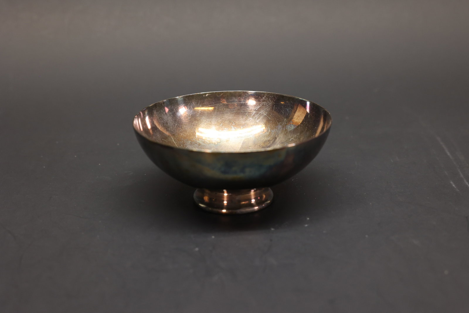 Sheffield Silver Co. Footed Bowl, Silver Plate: Small round footed bowl in silver plate, plain form with a flared rim on a stepped circular foot. Marked "The Sheffield Silver Co., Made in U.S.A." on the underside.Dimensions: H: 2", W: 4.25"