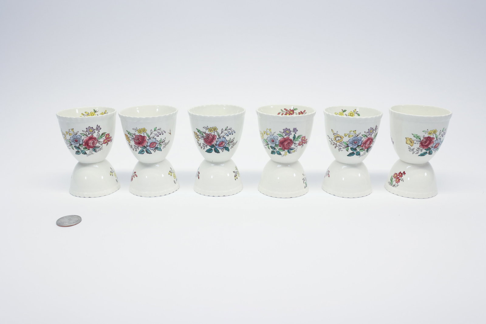 Copeland Spode "Romney" Egg Cups, Set of 6: Set of six earthenware double-ended egg cups in Copeland Spode's "Romney" pattern, gadroon-edged rims transfer-printed in polychrome with a rose-centered floral bouquet, matching sprig motif on the re