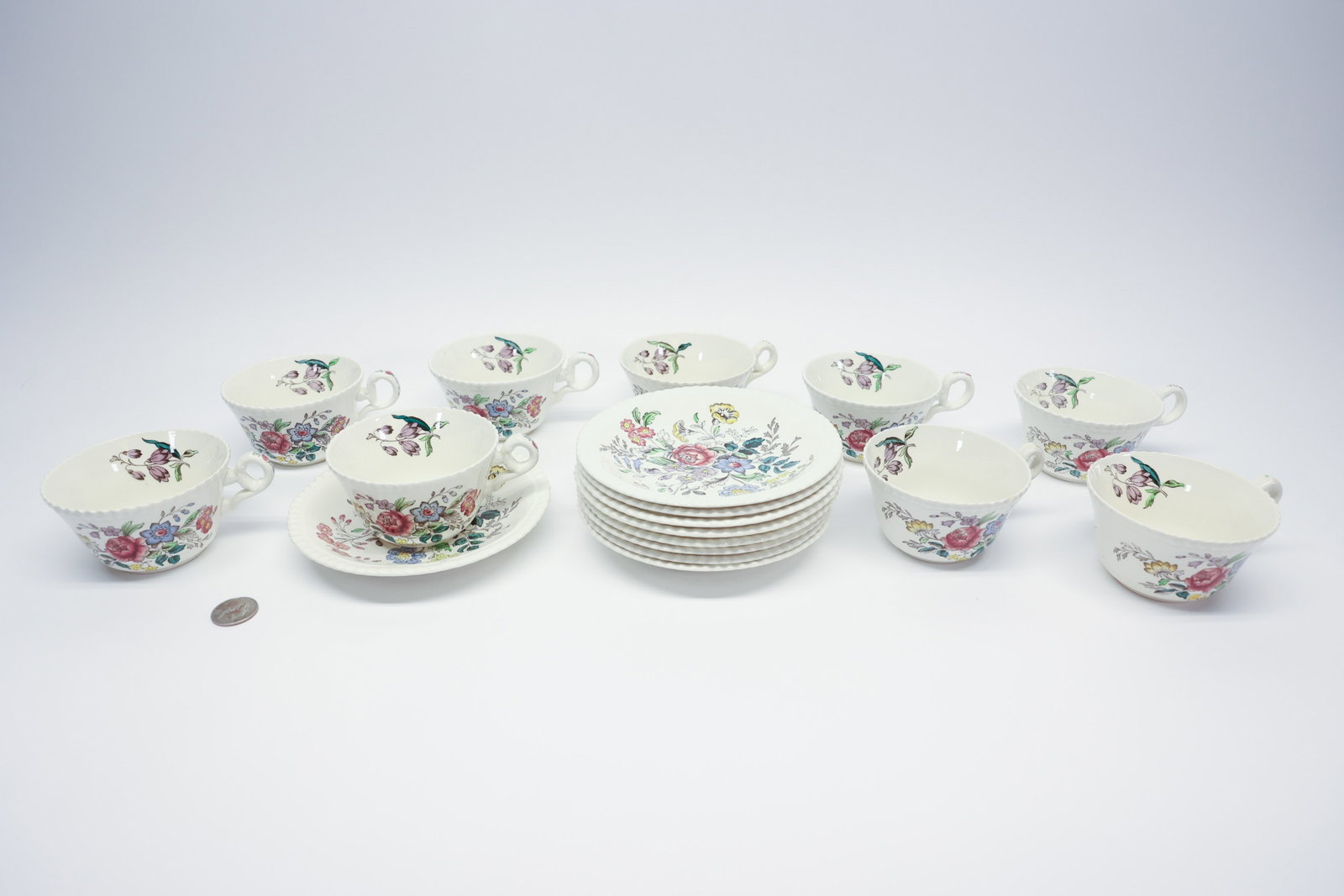 Copeland Spode "Romney" Cups & Saucers, Set of 9: Set of nine footed earthenware teacups with matching saucers in Copeland Spode's "Romney" pattern — loop handles, gadrooned rims, and a polychrome transfer-printed floral bouquet on each saucer with