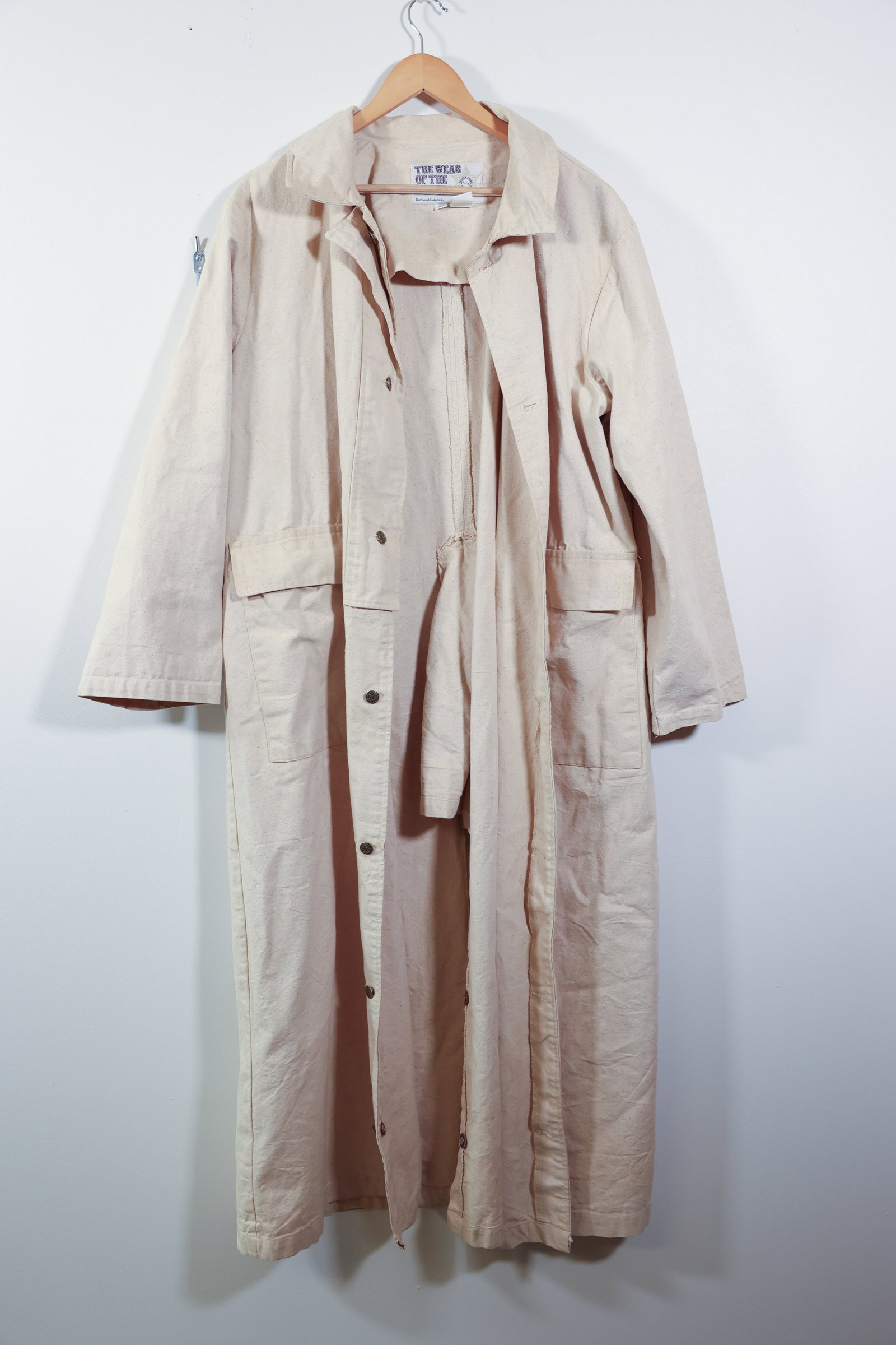 Vintage Wear of the West Canvas Duster Coat XL: Description:A vintage long duster coat in natural cream cotton canvas by "The Wear of the West," Berthoud, Colorado, labeled "Broken Spear Cattle Co." on the sewn-in brand tag with a star badge motif.