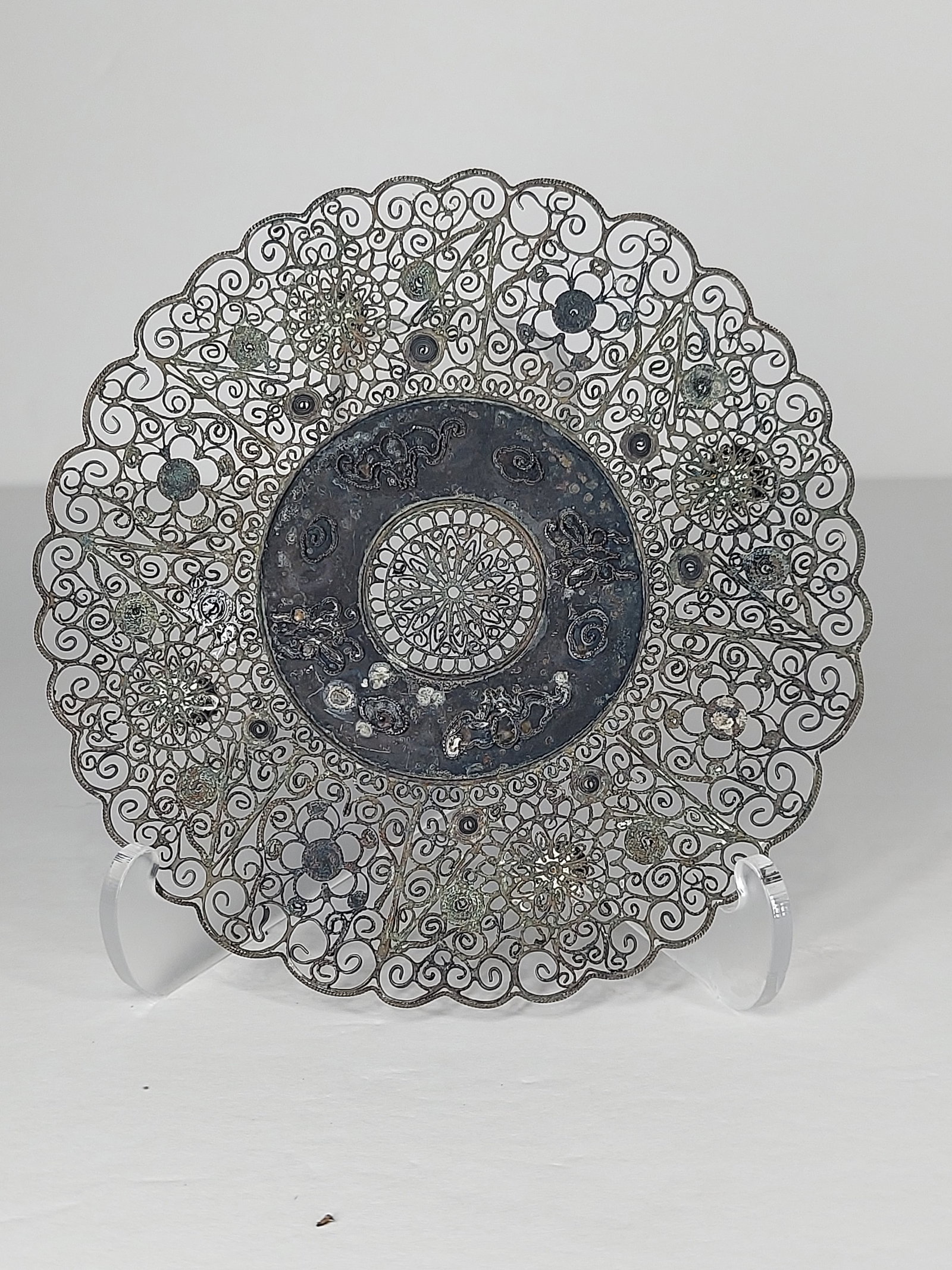 Silver Plate Filigree Art/Work: Silver Plate Filigree Decorative Art Plate This elegant silver plate features intricate hand-crafted filigree work with delicate floral motifs and flowing openwork scroll designs surrounding a