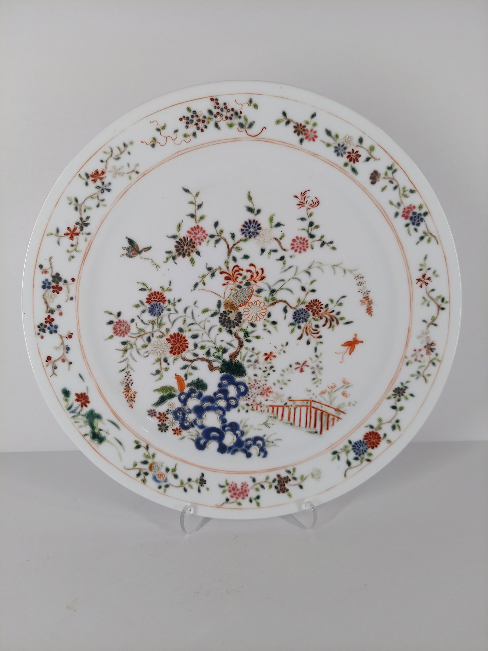 A FAMILLE ROSE FENCAI DISH YONGZHENG-QIANLONG PERIOD (1723-1795): A finely enameled famille rose fencai dish featuring a landscape and garden scene decorated with flowers, blue Scholar's rocks, leafy peony and chrysanthemum blossoms, butterflies, and a grasshopper.