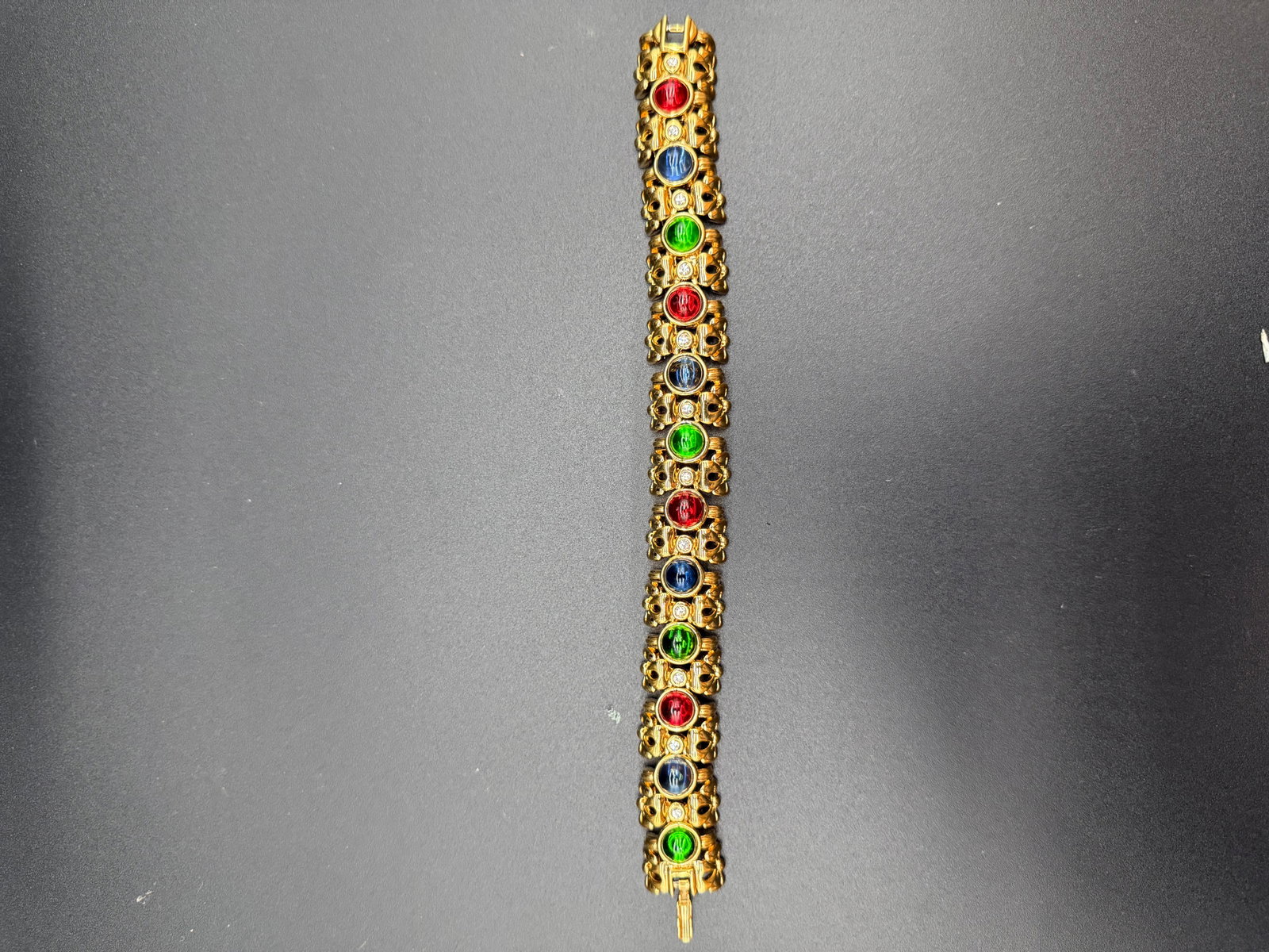 Nina Ricci gold tone Bracelet: Nina Ricci stamped Bracelet with Blue, Red, and green glass stones.
