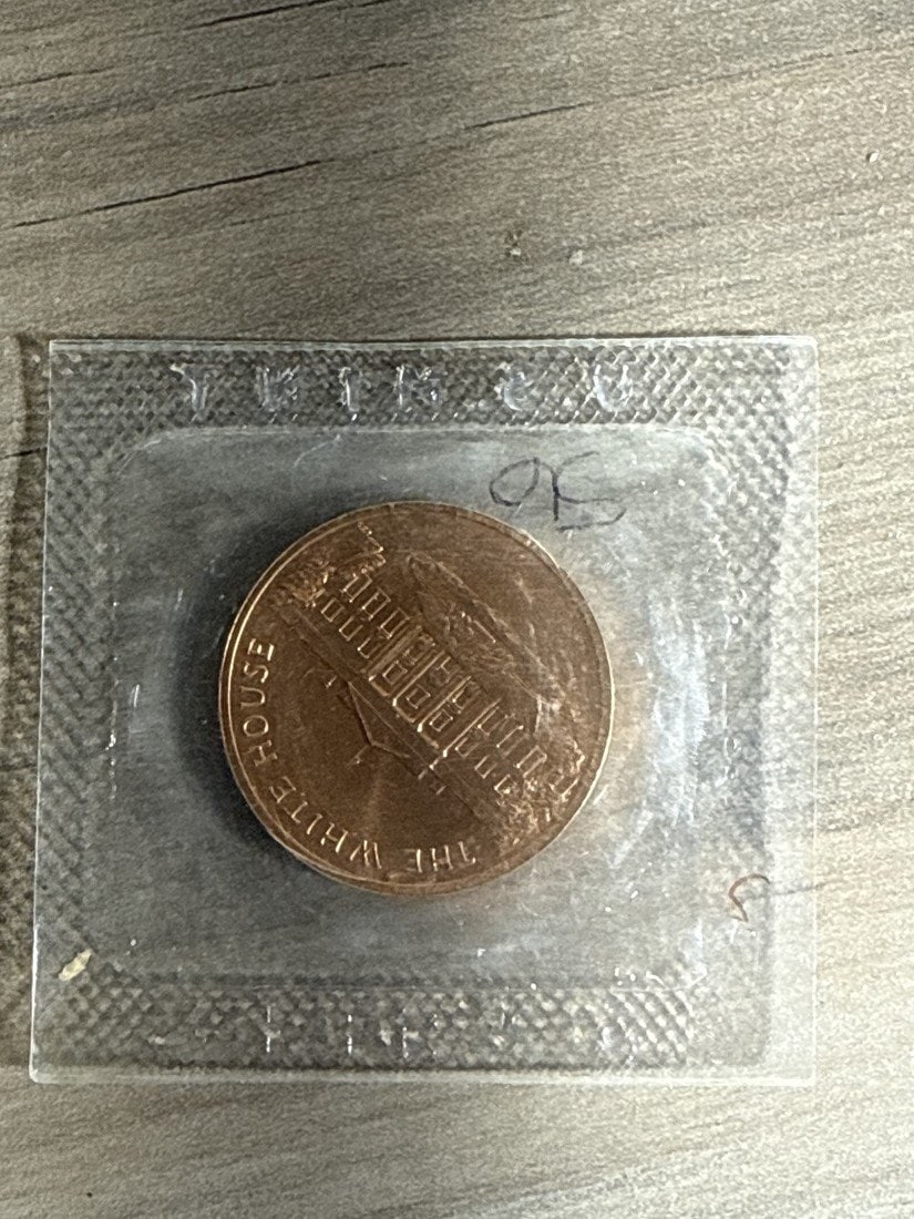 'The White House' Bronze Souvenir Medal, Sealed: Unopened in the Original Factory Pack A bronze souvenir medal of approximately 1-1/2 inches, still sealed in its original clear plastic pack exactly as issued. Obverse: the north facade of the White H