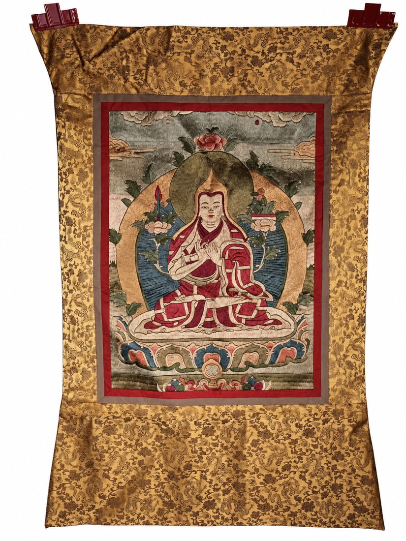 An Embroidered Thangka of Tsongkhapa, Attributed to the Qing Dynasty: An embroidered thangka depicting Tsongkhapa, attributed to the Qing dynasty, mounted within red and muted brown inner borders and a gold-colored floral brocade surround.Tsongkhapa is seated cross-legg