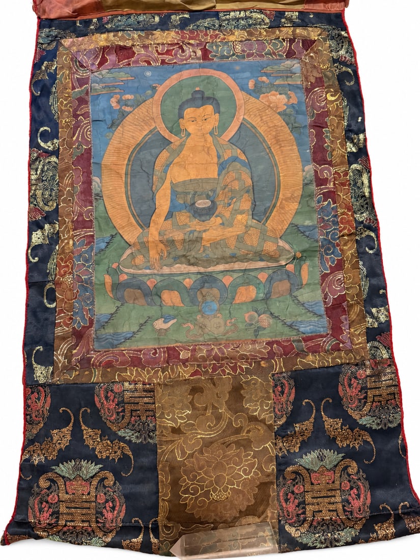 Thangka of Shakyamuni Buddha with Brocade Mounting: A thangka depicting Shakyamuni Buddha seated in vajra posture on a lotus pedestal, his right hand extended in the earth-touching gesture and his left supporting an alms bowl. The Buddha wears a patter