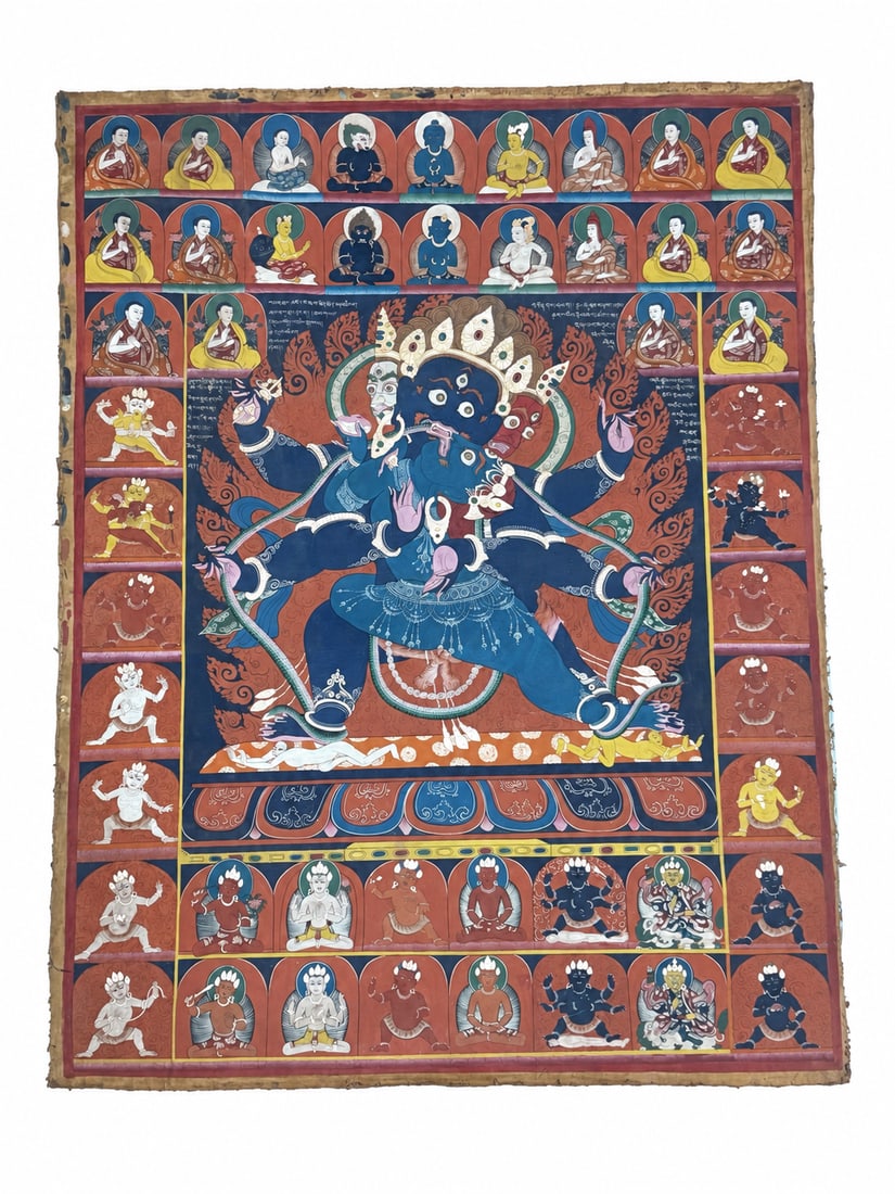 15-17 Century, Large Thangka of Mahachakra Vajrapani and Consort: A large thangka depicting Mahachakra Vajrapani in union with his consort. The three-faced, six-armed blue deity holds a vajra and a long serpent, standing above prostrate figures within an elaborate r