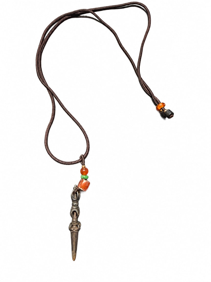 Yuan or Ming Dynasty, A miniature Tibetan crossed-vajra-form amulet combining three vajra terminals: A miniature Tibetan vajra-handled phurba-form amulet, featuring an openwork upper section, ringed collars and curled ornament above an elongated, tapering point. Fine decorative markings remain visibl