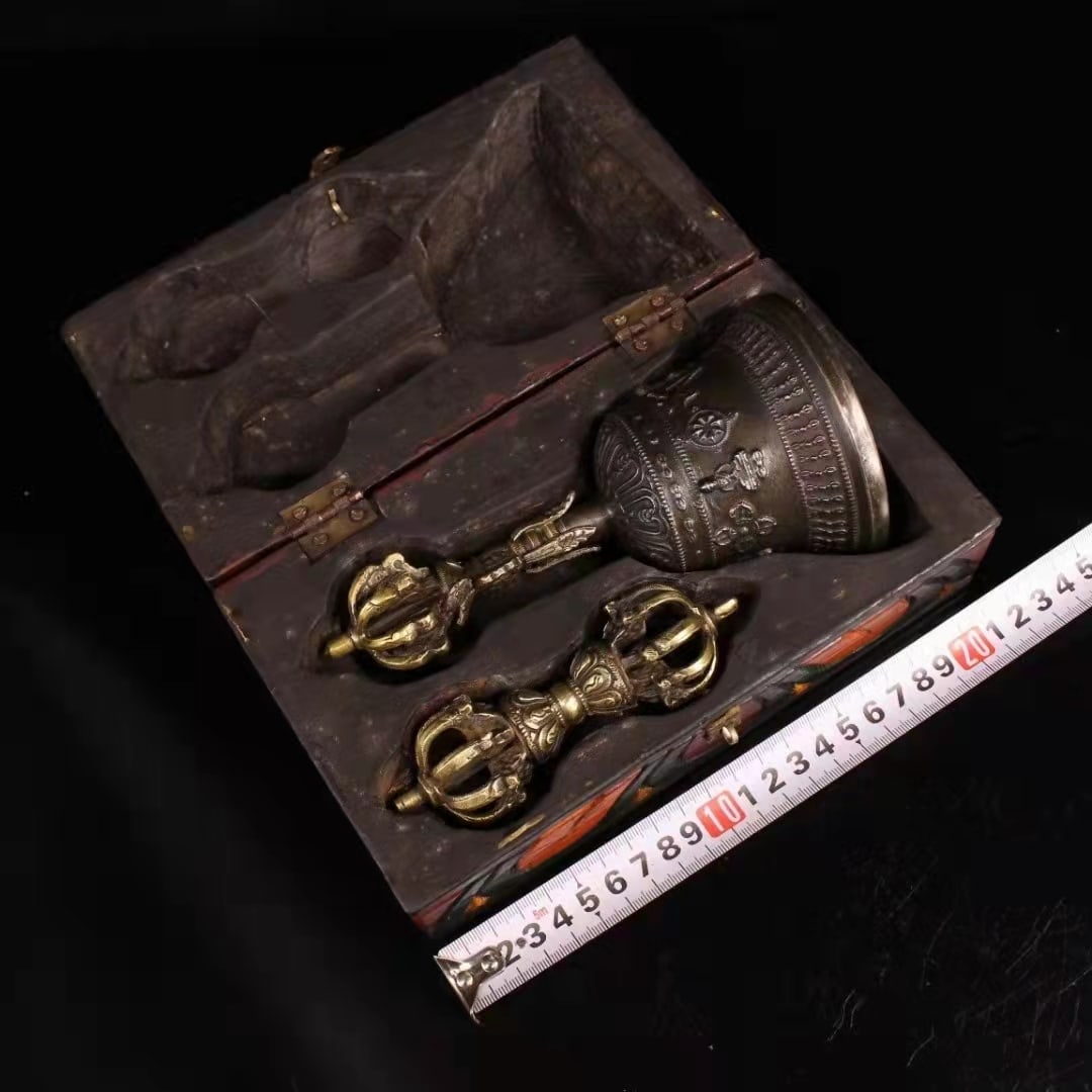 Qing Dynasty, Tibetan Ritual Bell and Vajra Set with Decorated Fitted Case: A Tibetan ritual set comprising a vajra and a ghanta bell, accompanied by a decorated fitted wooden case. The bell features a vajra-form finial above a crowned face, with its body ornamented in bands 