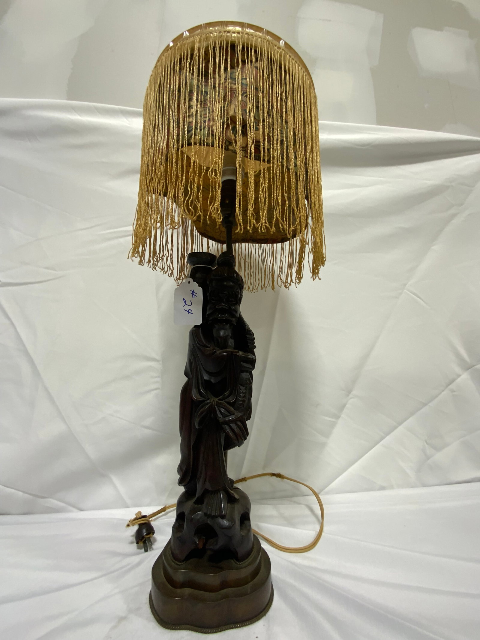 Oriental Lamp: Oriental lamp, carved wooden figure on brass base, shade has been married to it (not original), 10 inch shade, 34 inches tall.