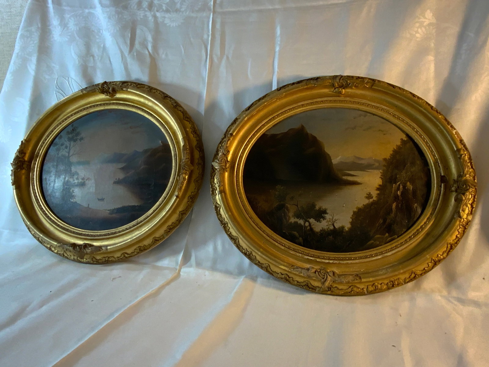 American Hudson River School Paintings: American Hudson River School circa 1860s, in oval rococo frames, pair of Hudson River School paintings of mountains and lake with boats, 9 1/2" x 11 1/2", gold frames, "MM Whitney" on a label on the