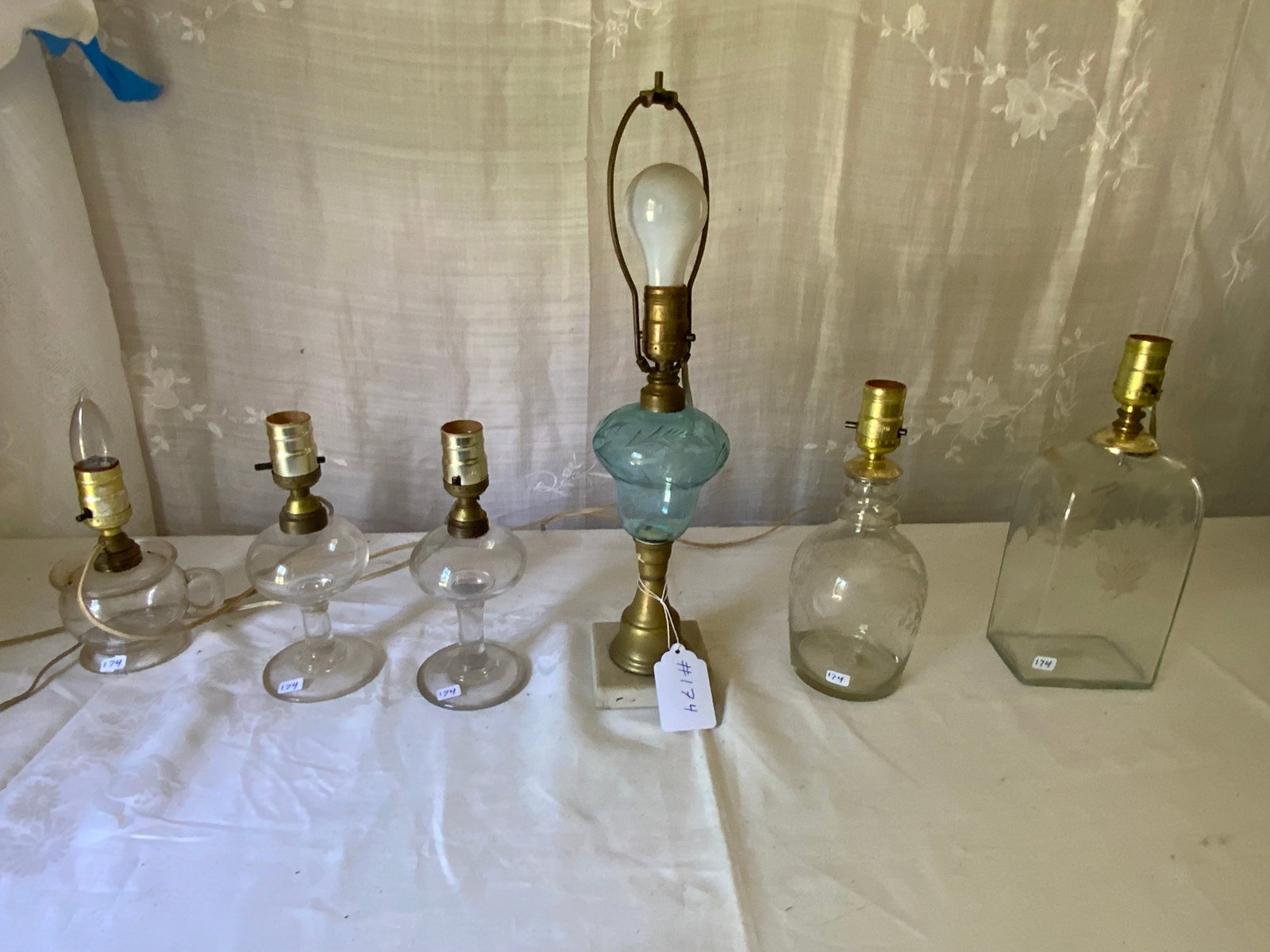 Early Lamps: Grouping of 6 early lamps, all electrified: 2 glass etched decanters made into lamps, 2 blown glass whale oil lamps, one blown glass finger lamp, and one brass and blue glass etched lamp with a