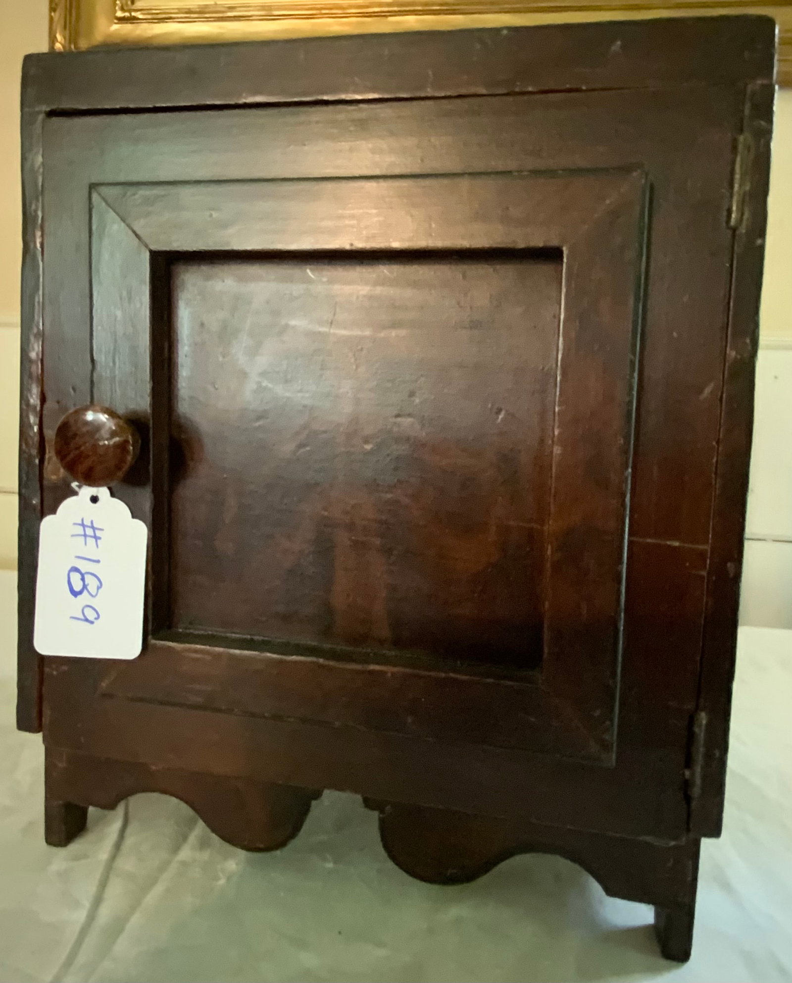 Table Top Cupboard: Table top cupboard, single door, compartmentalized interior, old dark grain paint w/ black striped border, cutout bracket ends. Good condition.