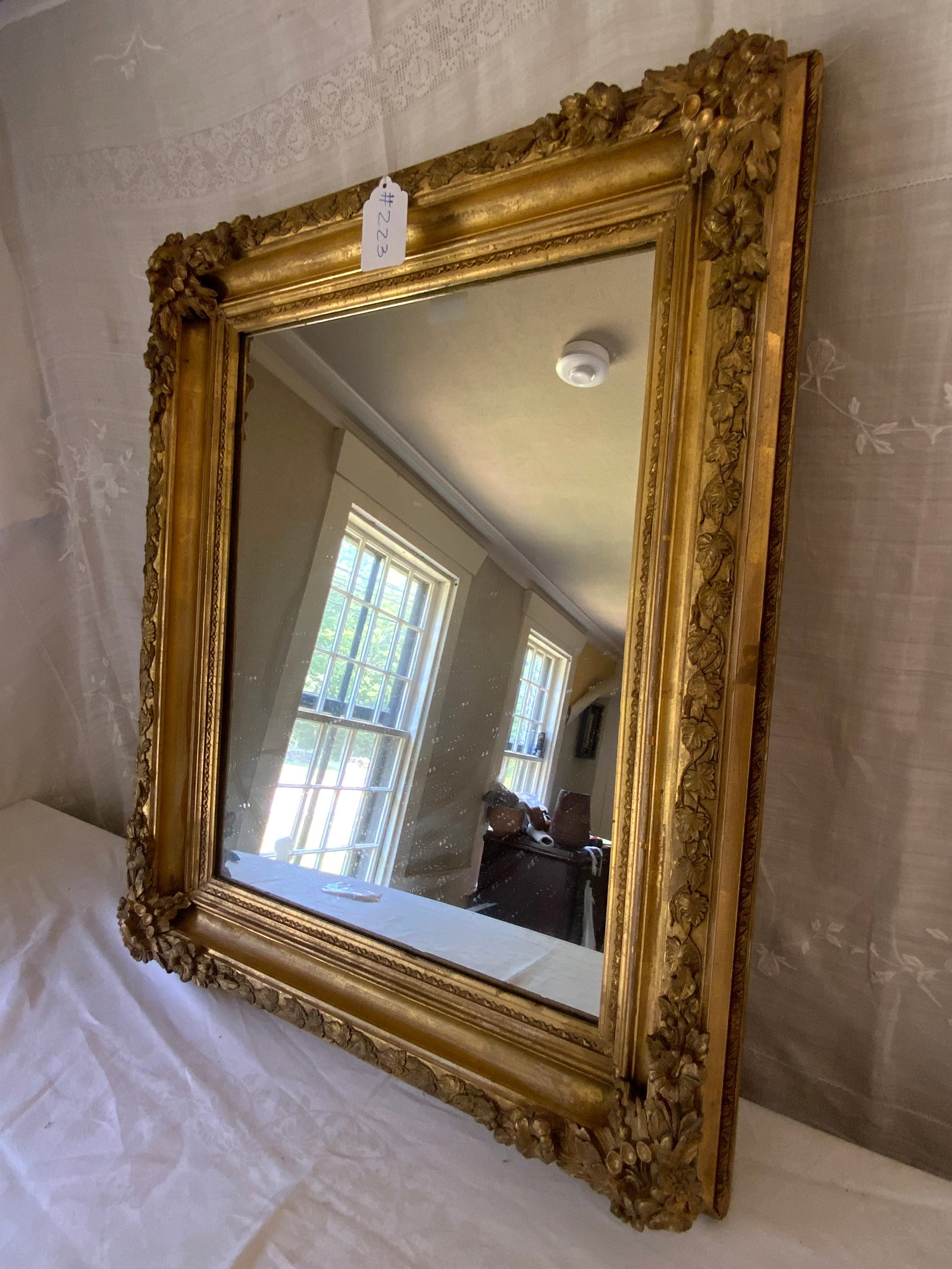 Classical Gold Gilt Mirror: Classical heavy gold gilt frame mirror with floral spirals joined by vines, 31 inches wide, 25 inches tall. Good condition.