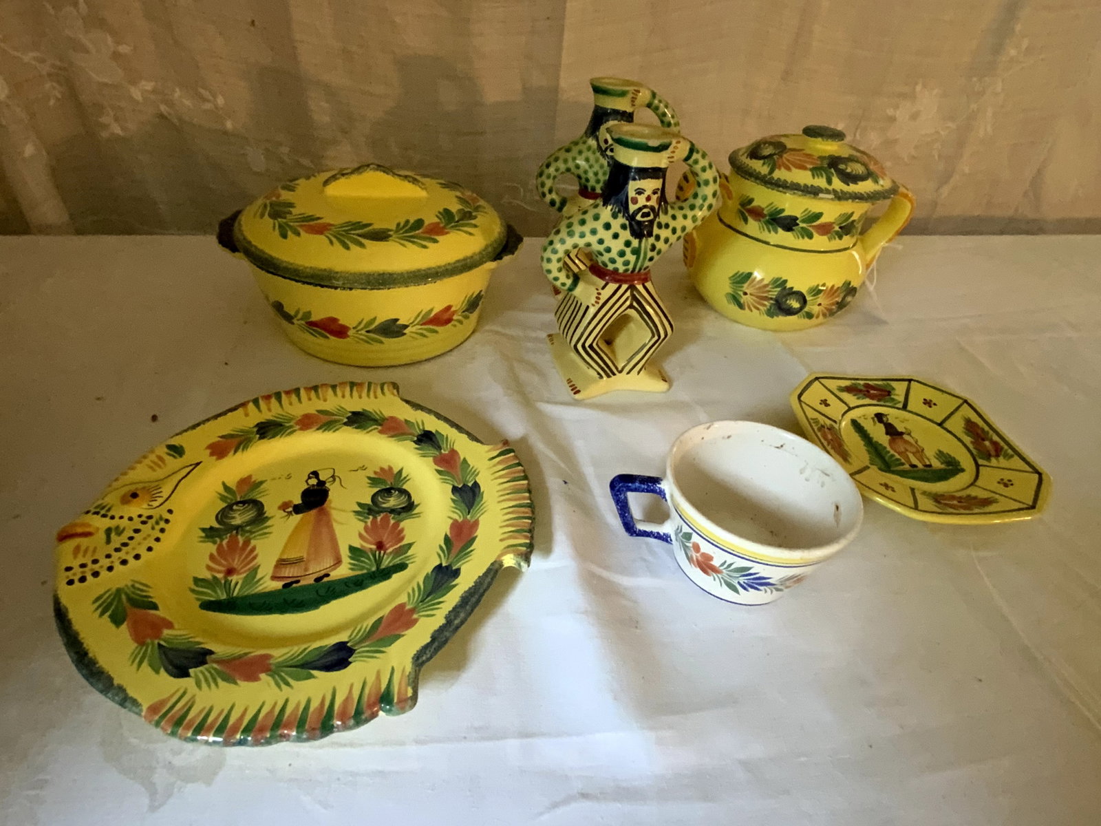Quimper Grouping: Grouping of Quimper (France), 7 pc: 2 candlesticks 8", fish plate w/ chip 10" tall, covered dish 10", 2-handle container 9" tall, small plate 6 1/2" x 6 1/2", coffee cup with crack. Various