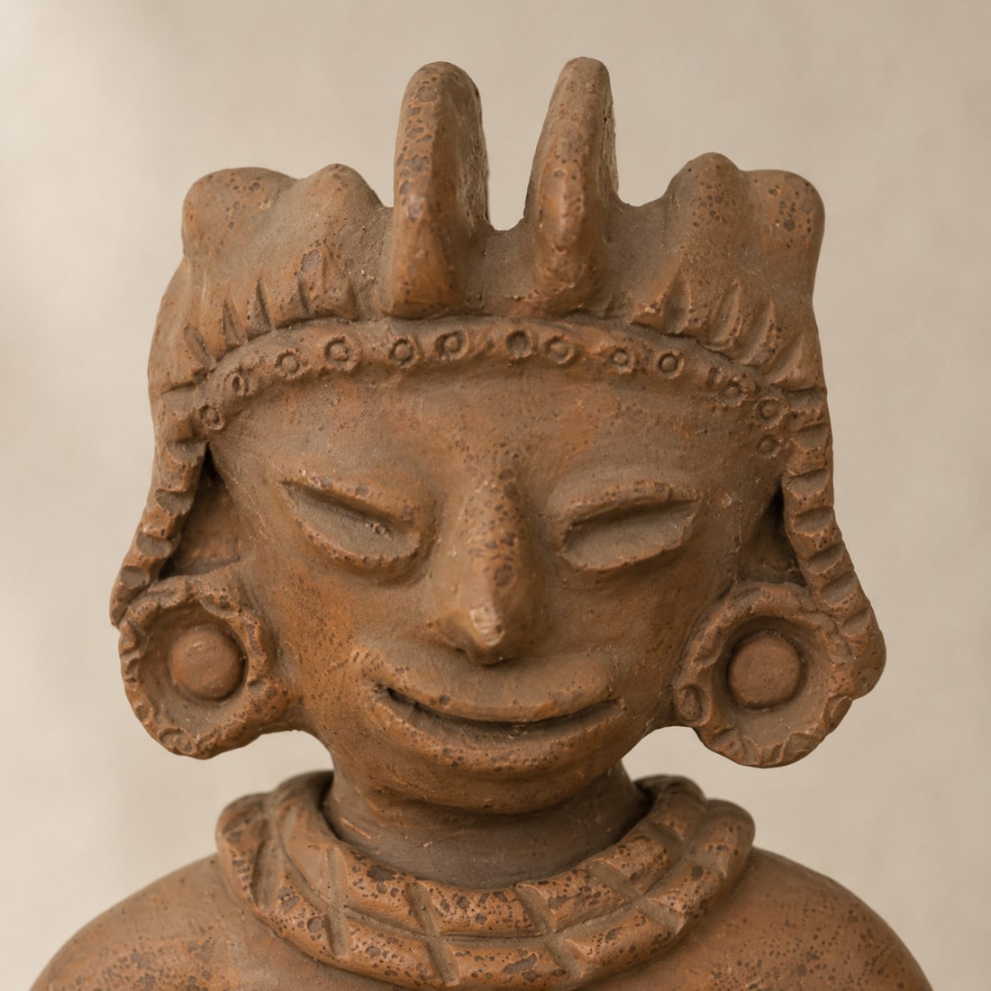 Pre-Columbian Style Terracotta Anthropomorphic Figurine: An aged terracotta anthropomorphic figurine, likely a reproduction or inspired by Pre-Columbian art. The figure features a serene, smiling face with closed eyes, large ear ornaments, and an elaborate 