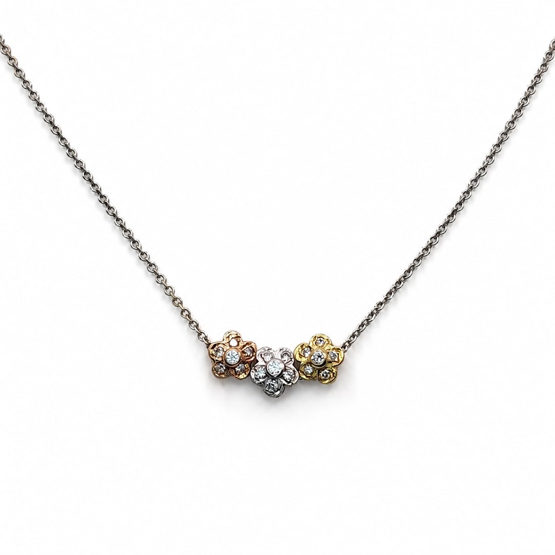 Gold and floral necklace: A 14kt gold necklace. Yellow, rose, and white gold diamond flowers on necklace. Each flower is .25x.25 inch. Diamonds are 0.18ct tw. White gold chain 16 inches. 3 grams. The flowers are moveable on